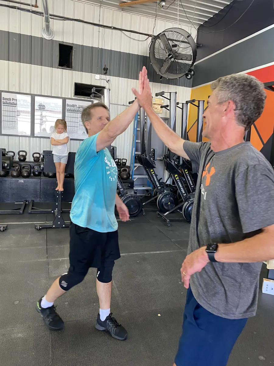 Two members high-five mid-workout